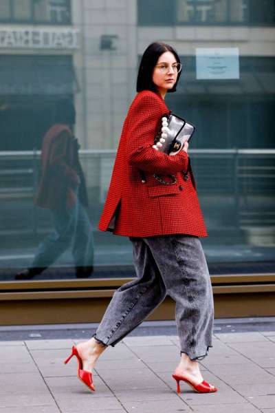 Девушка в серых широких джинсах, красный пиджак в клетку и красные мюли