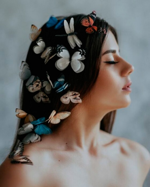 Девушка с естественным макияжем, распущенные волосы украшены бабочками