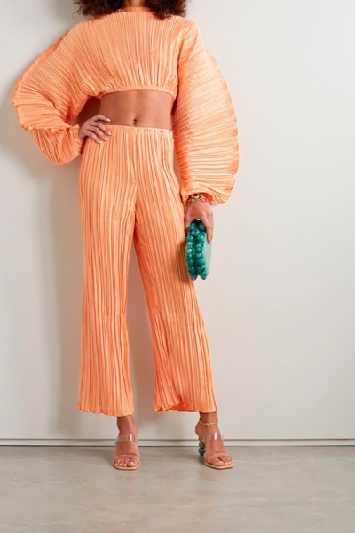 Модель в нежном персиковом костюме в складку с укороченным топом с объемными рукавами и свободные штаны
